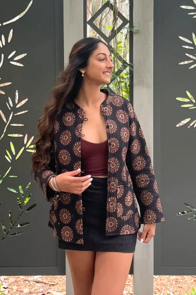 Harnoop wearing the  Quilted Cotton Jacket in black against a decorative wall.